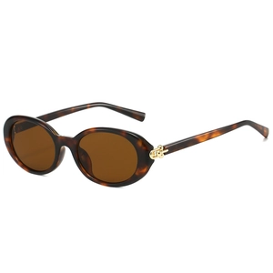 Retro oval tortoiseshell sunglasses with brown lenses and gold metal hinges on white background