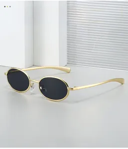 Close-up of golden oval metal frame sunglasses with black lenses on artistic background