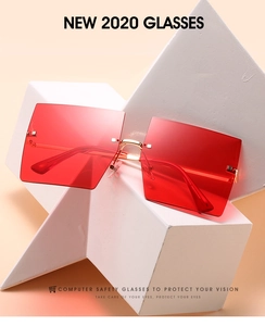 Detail of red rimless oversized sunglasses with gold metal bridge on geometric stand