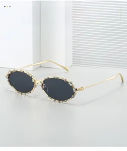 Detalle de gafas de sol ovaladas de metal con montura de pedrería y cristales oscuros
