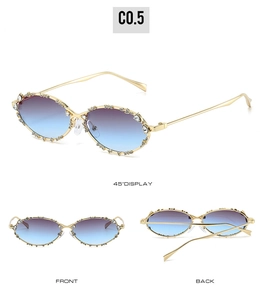 Detalle de gafas de sol ovaladas de metal con cristales incrustados y lentes en degradado azul