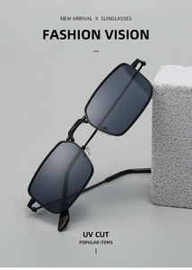 Detail of square black metal sunglasses with UV cut lenses on a grey decorative stone