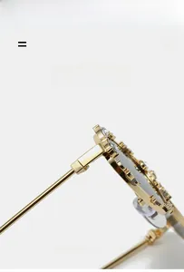 Detalle de gafas de sol ovales doradas con pedrería brillante y bisagras metálicas