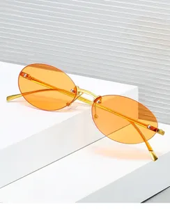Detail of rimless oval sunglasses with orange lenses and golden metal frames