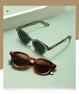Detail of round polarized sunglasses with rivet accents in transparent grey and amber frames