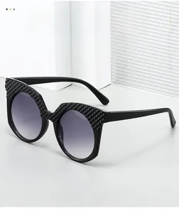 Detail view of oval sunglasses featuring a black quilted texture frame and gradient lenses