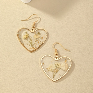 Boucles d'oreilles cœur dorées avec fleurs séchées blanches et feuilles d'or en résine