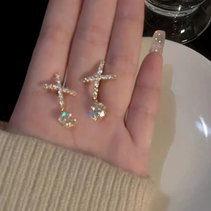 Détails de boucles d'oreilles croix dorées avec zircons et un grand cristal suspendu