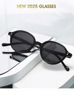 Detail of black oval sunglasses featuring silver double rivets on a white display stand