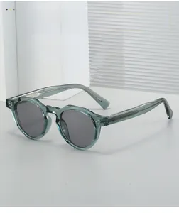 Close-up of vintage round sunglasses with transparent olive green frame and dark lenses