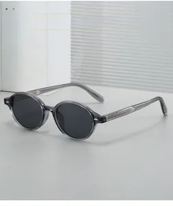 Detail showing translucent gray round frame sunglasses with textured metal temple inlay