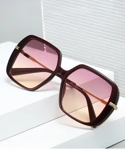 Gros plan de lunettes de soleil carrées oversize avec monture bordeaux et détails dorés