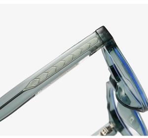 Detail shot of transparent grey blue eyewear frame showing embossed metal temple core
