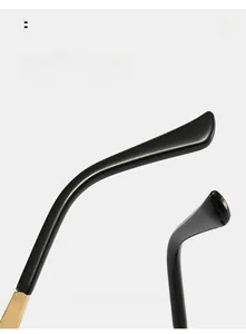 Detail of golden metal hinge with floral engraving and curved black temple for sunglasses