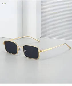 Détail d'une monture de lunettes de soleil carrée en métal doré avec verres foncés