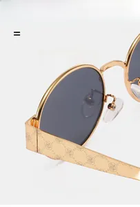Detail of gold metal oval sunglasses with intricate rose floral temple engravings
