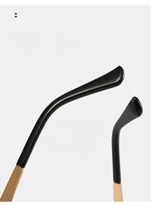 Detail of oval sunglasses temple with black curved arm and gold floral metal hinge