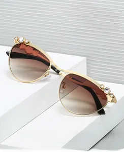 Detailansicht der ovalen Metall-Sonnenbrille mit Strasssteinen und braunem Verlauf