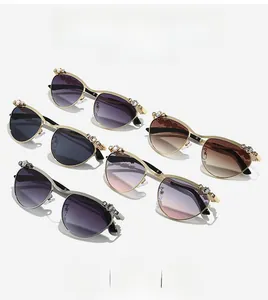 Detail einer luxuriösen ovalen Metall-Sonnenbrille mit Perlen- und Strassbesatz am Rahmen