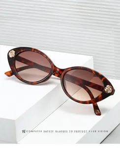 Detail of tortoise shell oval sunglasses with gold rose ornaments on a white display