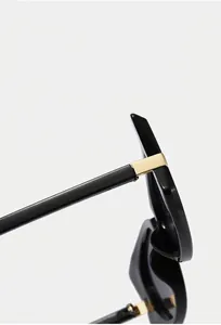 Détails de lunettes de soleil papillon noires avec charnière dorée et matériau texturé
