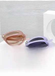 Details von faltbaren ovalen Sonnenbrillen in Pfirsich und Lavendel auf weißem Ständer