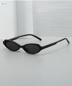 Side view of sleek black oval sunglasses on a minimalist grey surface with textures