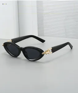 Détail de lunettes de soleil œil-de-chat noires avec chaîne dorée et pointes sur les branches