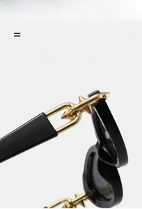 Vue détaillée des lunettes de soleil noires avec chaîne dorée et rivets à pointes coniques