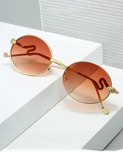 Detail of vintage oval gold metal sunglasses with orange gradient lenses and S-shaped temple