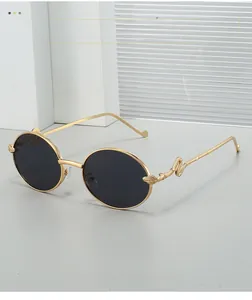 Detail of vintage oval sunglasses featuring a golden snake-shaped carved metal temple