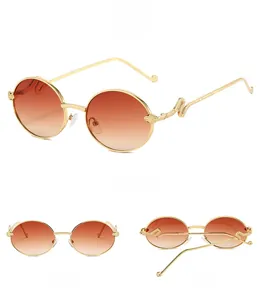 Detail of gold metal oval sunglasses with orange lenses and snake carved temples