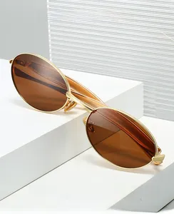 Detail of oval golden metal sunglasses with brown lenses on a white display stand
