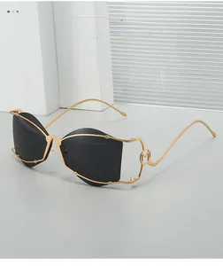Détail de lunettes de soleil en métal doré avec verres noirs et branche en forme de M