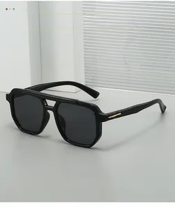 Close-up of black pilot sunglasses with gold metal accents on textured stone background