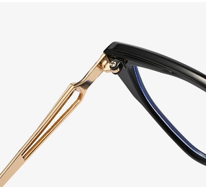 Macro shot of gold geometric metal hinges and black temples on cat-eye glasses
