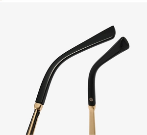 Detail of elegant black and gold cat-eye eyeglass temples with precise hinge screws