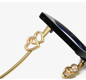 Detail of gold double-heart hinge on black cat-eye glasses with blue coating