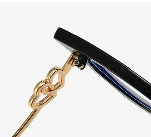 Detail of black cat-eye frames with golden double-heart metal hinges and sleek temples