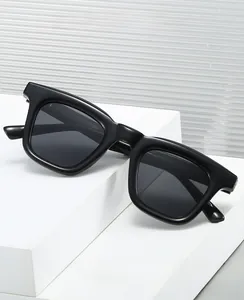 Close-up of thick black rectangular sunglasses on a white stepped display stand