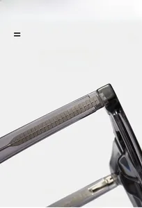 Detail view of transparent grey eyewear arm with textured metal core and hinge