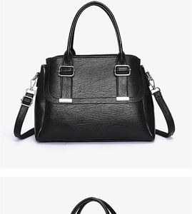 Close-up of black textured leather bag showing silver metal buckles and tassel details