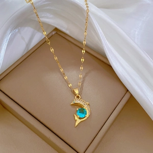 Elegante collana con ciondolo a delfino dorato con gemma blu e zirconi su sfondo di seta