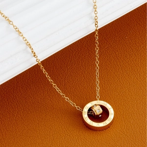 Close-up of golden necklace with Roman numeral ring pendant and micro-set zircon stone