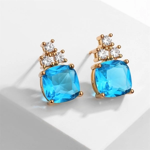 Macro shot of geometric sky blue zircon earrings with a golden metal finish on white stand