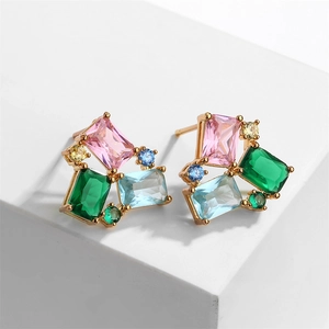 Macro shot of geometric gold stud earrings with colorful zircon stones on white background