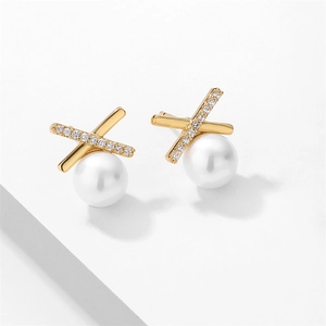 Gros plan de boucles d'oreilles dorées en X avec zircons et perle ronde tombante