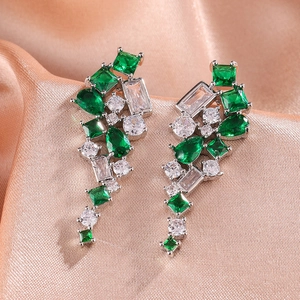 Vue macro de boucles d'oreilles en zircon avec pierres vertes et claires sur soie