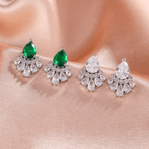 Boucles d'oreilles argentées avec zircons poire verts et clairs sur tissu en soie rose