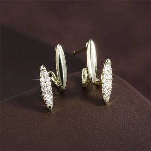 Macro shot of curved gold-plated earrings with pavé set cubic zirconia and polished surface